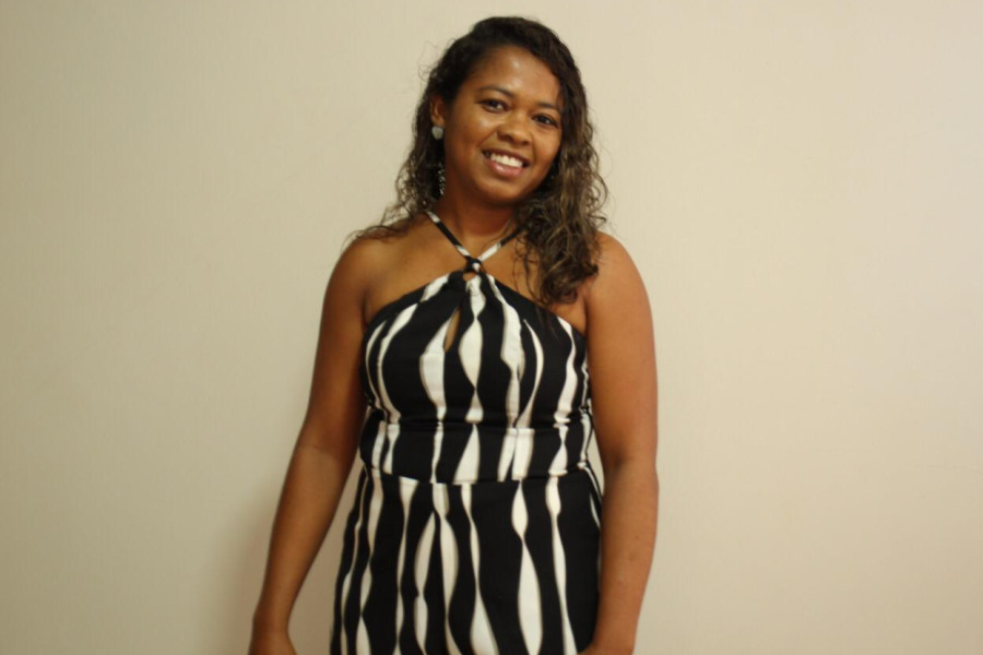 Ana Lúcia de Abreu, ao centro da foto, com vestido listrado preto e branco, sorri