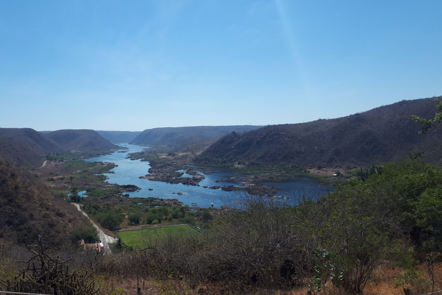 Imagem aérea do Rio São Francisco cercado por pequenas montanhas verdejantes em suas margens com vegetação típica da Caatinga
