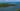 Fotografia de Paisagem de encontro de rio com o mar com águas de coloração predominantemente azulada com uma faixa de terra coberta de vegetação onde se destacam coqueiros e praias de areia branca às margens