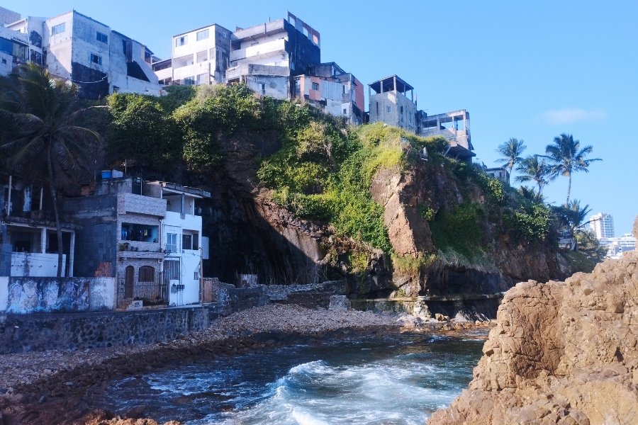 Na beira da praia, há cerca de dez casas construídas sobre ou na base de uma pedra. A pedra tem aproximadamente 30 metros. Fragmentos de vegetação rasteira e coqueiros cercam a estrutura rochosa