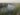 Foto de rio feita do alto com cacto à esquerda em primeiro plano, no centro o leito do rio e nas laterais cânions cobertos de vegetação rala sob céu nublado com a silhueta de montanhas à esquerda no fundo da imagem