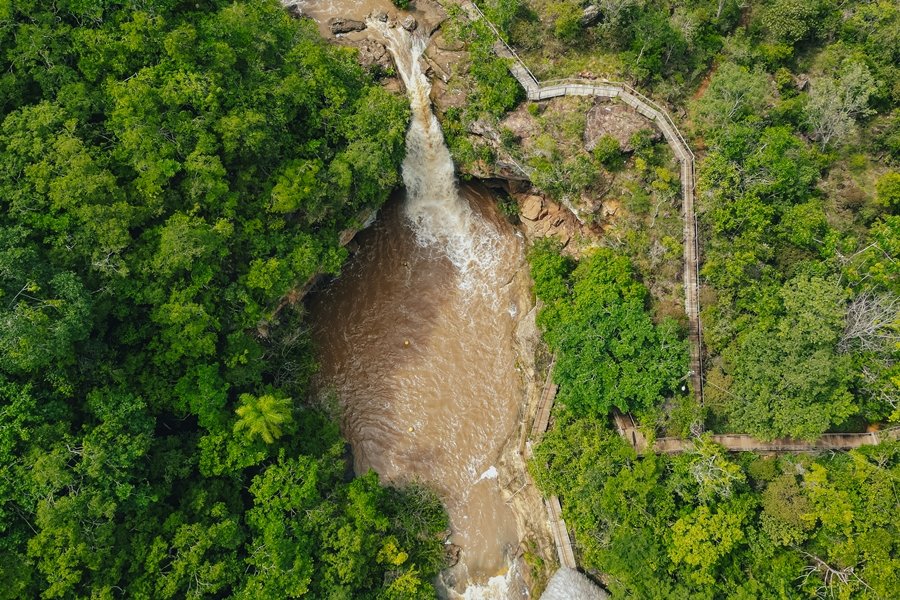 Imagem aérea colorida de uma grande cachoeira de águas turvas e espumosa caindo em meio a vegetação de Cerrado