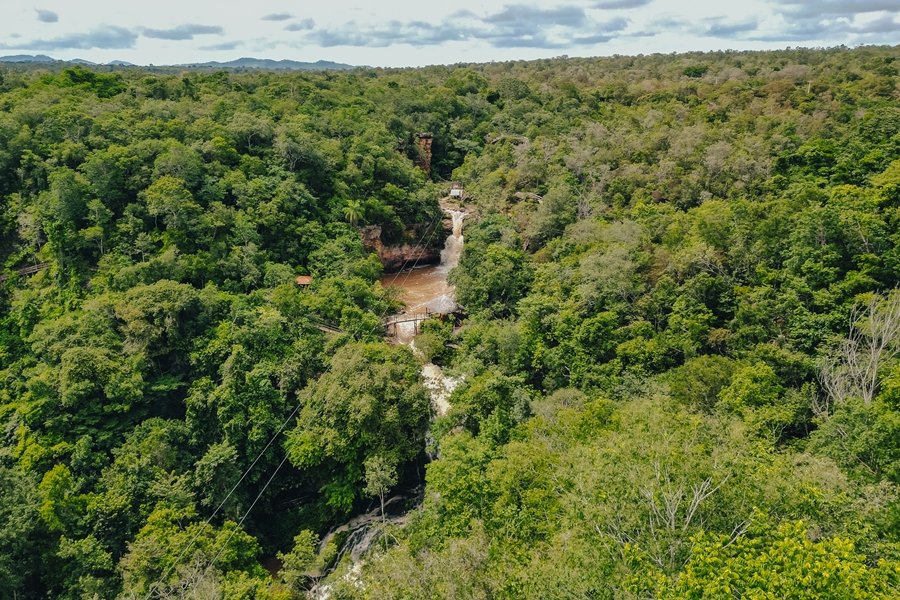 Foto aérea de uma enorme queda d’água de águas turvas caindo em meio a vegetação densa do Cerrado