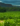 Fotografia de uma encosta montanhosa coberta e rodeada por vegetação nativa de cerrado que vai dando lugar á uma grande plantação de soja verde sob um céu nublado