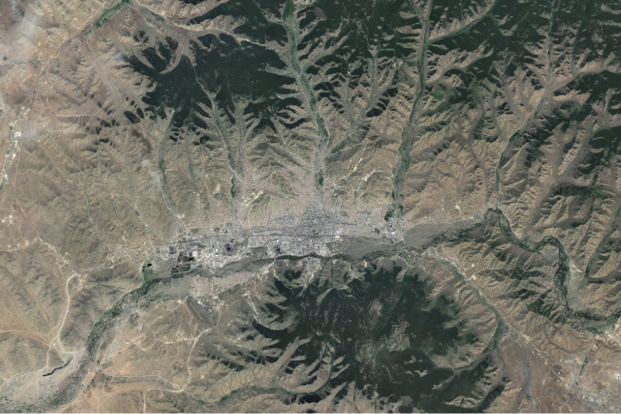 Imagem de satélite mostrando uma área urbana estabelecida ao longo de um vale, cercada por relevo montanhoso e vegetação.