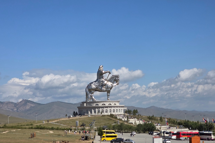 Uma imponente estátua prateada de Genghis Khan a cavalo se destaca em uma colina sob o céu aberto.
